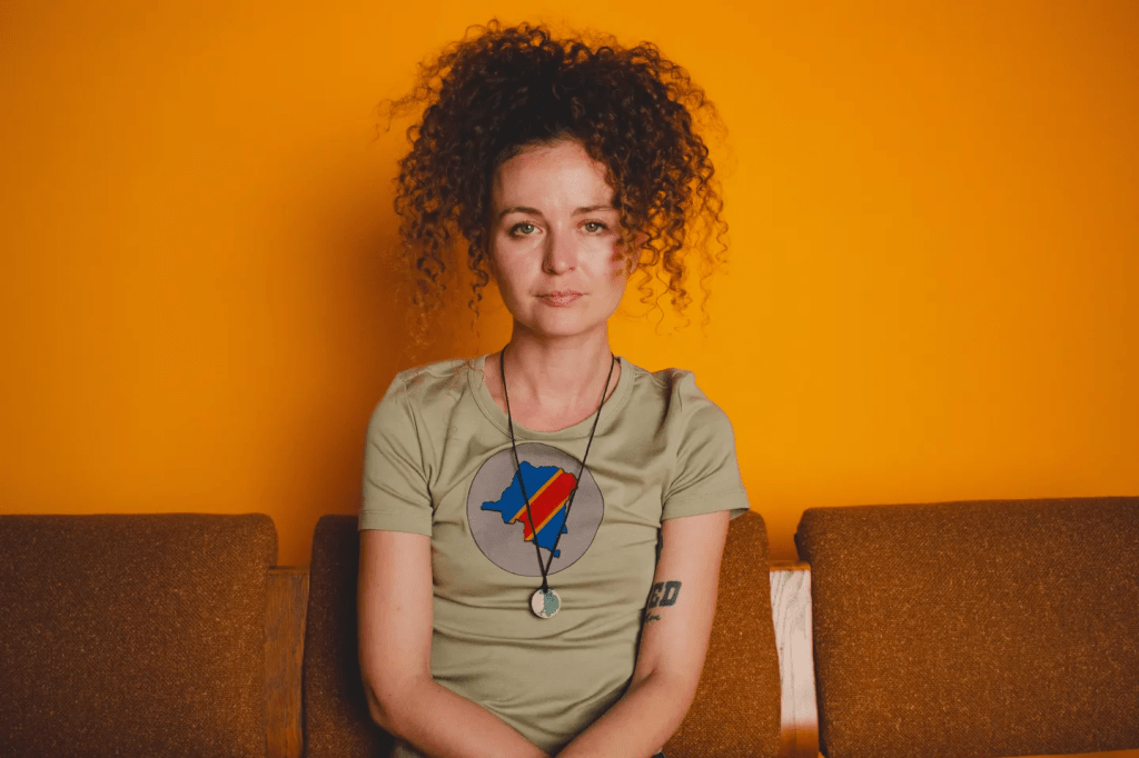 Woman, Music, Musician, Artist, Singer, Tattoo, Yellow, Wall, Background, Couch, Seat, Curly, Hair, Chain, Jewellery